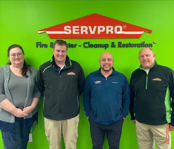 our team against a green wall with a SERVPRO logo background
